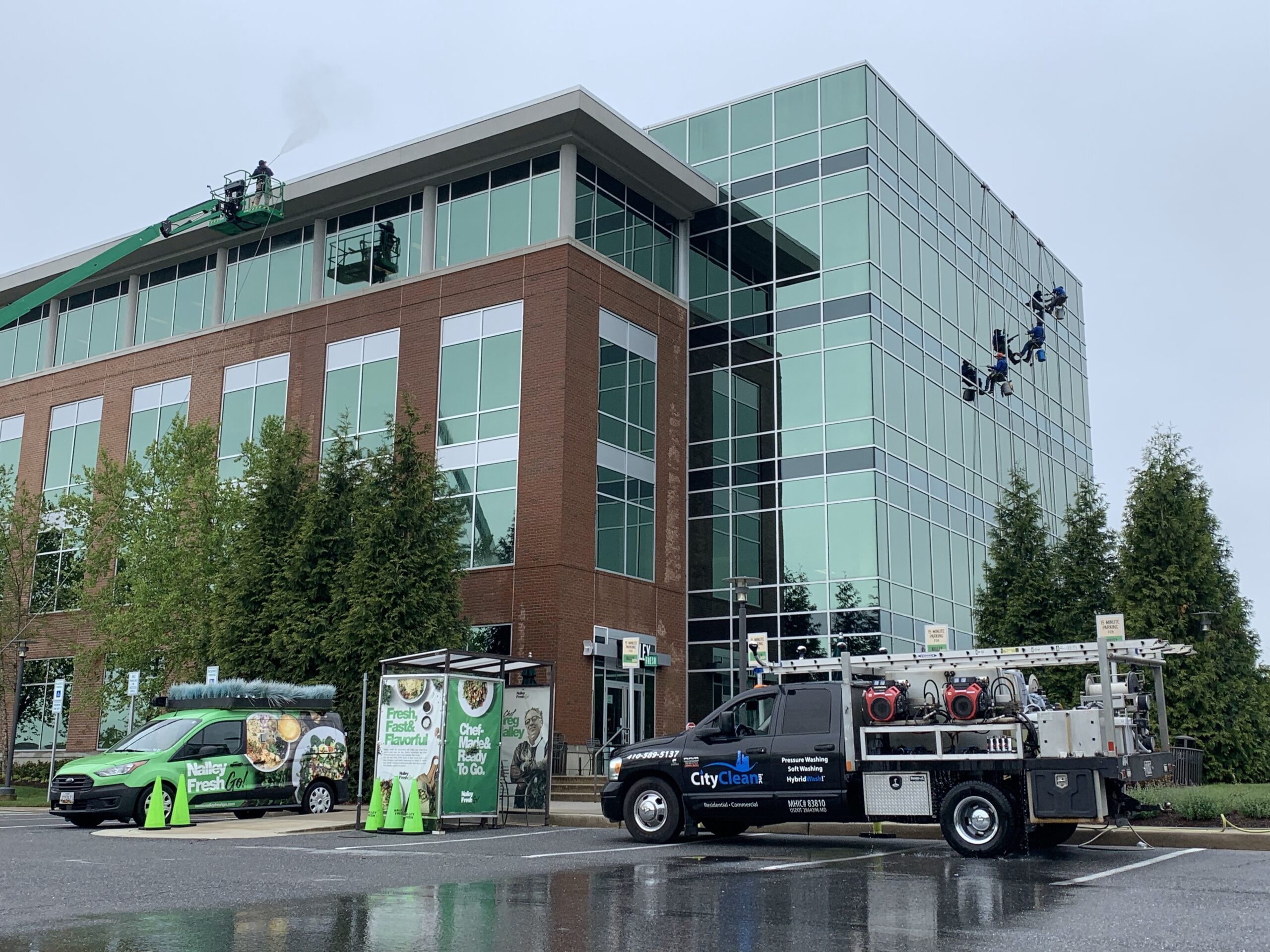Commercial building exterior with window cleaners and service vehicles in Crofton, MD.