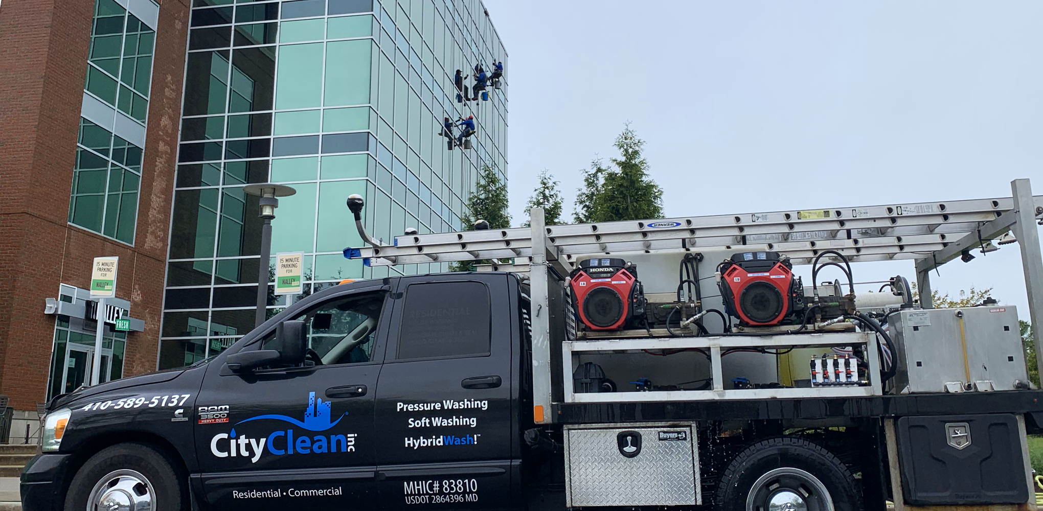 Glass office building with professional window cleaners working on the exterior in Severna Park, MD.